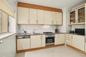 a kitchen with white cabinets and a sink at Brisa Do Mar Moura Beach in Quarteira