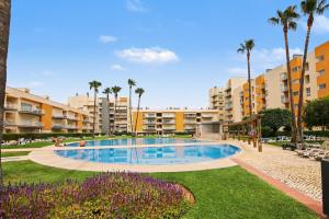 a swimming pool in a resort with palm trees and buildings at Brisa Do Mar Moura Beach in Quarteira