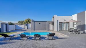 a patio with chairs and a swimming pool in front of a house at Cozier Glitz in Cape Town