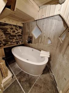 a white bath tub in a bathroom with a stone wall at Casa Piazzo Due in Brusio