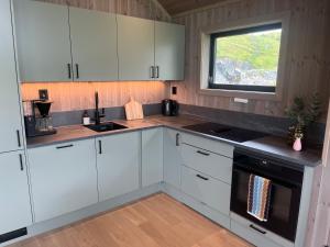 a kitchen with white cabinets and a window at Lofoten Arctic Cabin in Sørvågen +40 photos