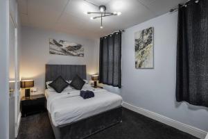 a bedroom with a bed and two windows at 100 Pipers Hotel in Blackpool