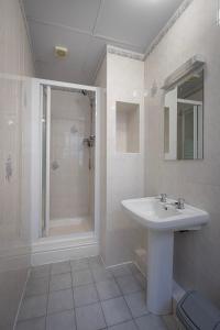 a white bathroom with a sink and a shower at 100 Pipers Hotel in Blackpool