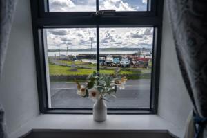 a window with a vase of flowers on a window sill at Harbour View - Sleeps 26 guests in Liscannor