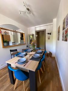 a dining room with a long table and blue chairs at Le Grand 27 in Guebwiller