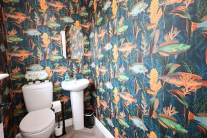 a bathroom with a toilet and a tropical wallpaper at Harbour View - Sleeps 26 guests in Liscannor +24 photos