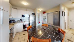 a kitchen with a black marble table and chairs at Snow Ghost Inn 220 by Okanagan Premier in Big White