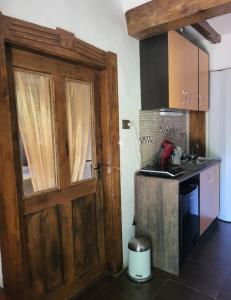 a kitchen with a wooden door and a stove at BODZA Apartment in Tompa