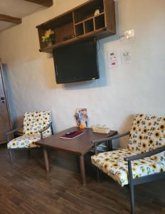 a room with two chairs and a table and a tv at BODZA Apartment in Tompa