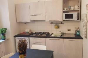 a kitchen with white cabinets and a stove and microwave at Casa della Ludo Biella in Biella