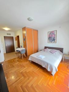 a bedroom with a large bed and a wooden floor at Laki Apartment in Podgorica