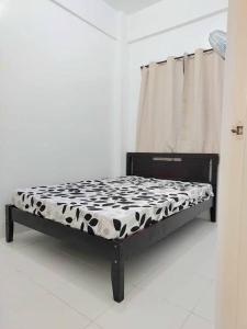 a bed with a black and white comforter on it at Bautista Apartments in Imus