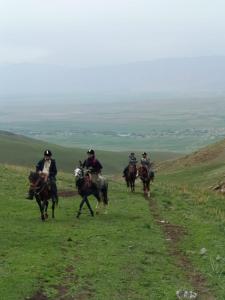 a group of people riding horses down a hill at Oskon Guesthouse in Kyzart