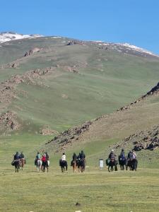 a group of people riding horses in a field at Oskon Guesthouse in Kyzart