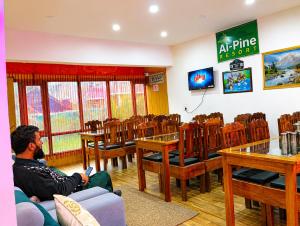 a man sitting in a room with tables and chairs at Hotel alpine resort pahalgam in Pahalgām
