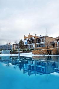 uma piscina com água azul em frente a um edifício em Nymfasia Resort em Vytina