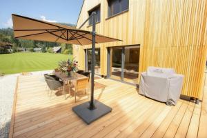eine Holzterrasse mit Tisch und Sonnenschirm in der Unterkunft Frein Chalets - Oberfrein in Frein