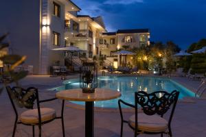 Ein Tisch und Stühle neben einem Swimmingpool bei Nacht in der Unterkunft Maryan in Limenas