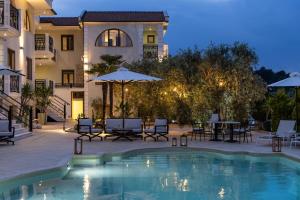 ein Pool mit Liegestühlen und Sonnenschirmen neben einem Gebäude in der Unterkunft Maryan in Limenas