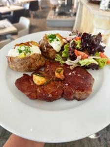 a plate of food with meat and a salad on it at Hotel Praha in Špindlerův Mlýn +45 photos