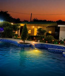 a swimming pool at night with a building in the background at Poolside Paradise in Ghaziabad