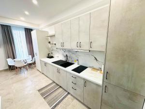 a kitchen with white cabinets and a sink and a table at Tanushi Central Apartments in Vau i Dejës