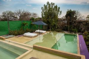 a swimming pool with an umbrella in a garden at Hotel Boutique Casa Isabella in Tepoztlán