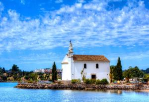 een witte kapel op het water met een blauwe hemel bij Filippas Rooms in Gouvia in Gouvia