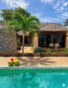 a villa with a swimming pool and a house at Kuarasy Pousada de Charme Japaratinga in Japaratinga