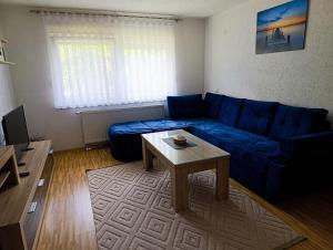 a living room with a blue couch and a table at Apartmani Srebrenik in Srebrenik