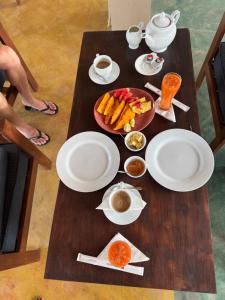 a table with plates of food and a bowl of fruit at Sound Sleep Resort in Arugam Bay