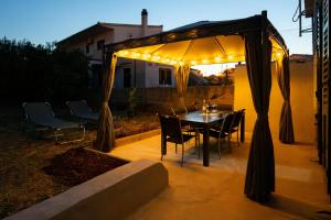 a table and chairs under a canopy with lights at Kathy House in Slatine
