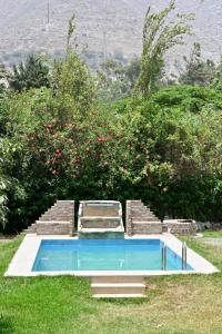 a swimming pool in the grass next to some bushes at Chatowasi Mountain Lodge in Santa Eulalia