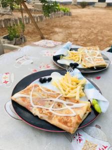 two plates of food and french fries on a table at La tente tamaghza in Tamaghzah