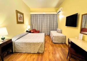 a hotel room with a bed and a chair at Dayrell Hotel e Centro de Convenções in Belo Horizonte