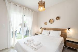 a bedroom with a white bed with two towels on it at EriZen Jacuzzi suites in Keramoti +64 photos