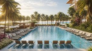 an infinity pool with chaise lounge chairs and palm trees at Beach Park Resort - Ohana in Aquiraz