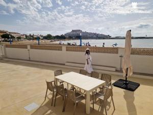 a woman standing next to a table next to the beach at Villa Brisamar - On the beach in Peniscola