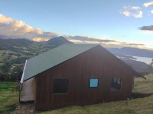a barn sitting on top of a hill with a sunset at Glampin la esperanza vista al embalse in Guatavita
