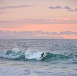 a man riding a wave on a surfboard in the ocean at Hotel Punta Sirena in Curanipe