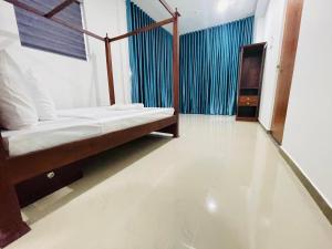 a bedroom with a bed and a blue curtain at Kalupahana Villa in Beruwala +4 photos