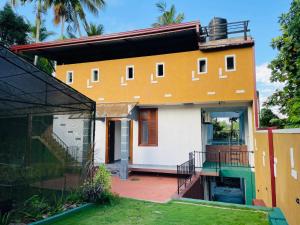 a yellow and white house with a yard at Kalupahana Villa in Beruwala