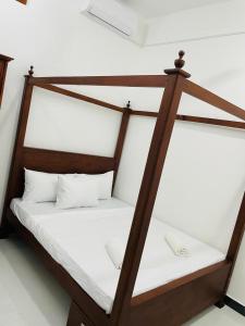 a wooden bed with white sheets and white pillows at Kalupahana Villa in Beruwala