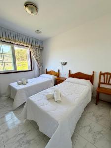 a bedroom with two beds and a window at Casa Rodiño in Meaño