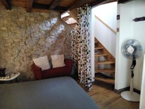 a room with a stone wall and a red chair at Maison de la Source in Leychert