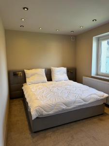 a bedroom with a bed with white sheets and a window at Apartament Powidz in Powidz