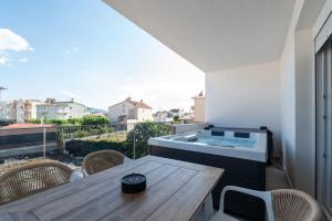 a balcony with a wooden table and a hot tub at EriZen Jacuzzi suites in Keramoti