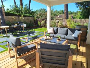 a patio with a couch and chairs on a deck at Villa Céline - Prestige, Piscine & Jacuzzi in Vielle-Saint-Girons