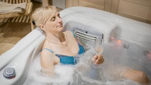 a woman in a bath tub with a glass of champagne at Bohinj Mountain Dreams in Bohinj +54 photos