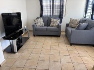a living room with two chairs and a flat screen tv at josedith'sweet house in Isabela